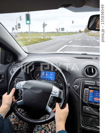 A Ford Mondeo with a woman's hands on the steering wheel drives along an autumn country road. A Ford Mondeo with a woman's hands on the steering wheel drives along an autumn country road. 135836549