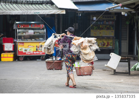 Woman carrying a basket of food on her back Woman carrying a basket of food on her back 135837335