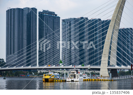 Yellow boat is on the water near a bridge 135837406