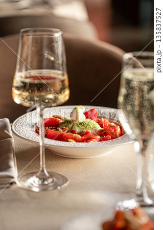 Burrata with tomatoes served with white wine Burrata with tomatoes served with white wine 135837527