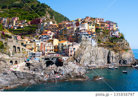 Multicolored houses on cliff edge. Manarola Italian village Cinque Terre Liguria, Italy. Summer sea Multicolored houses on cliff edge. Manarola Italian village Cinque Terre Liguria, Italy. Summer sea 135838797