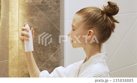 Teen girl spraying facial mist, skincare and wellness routine in a modern bathroom. Blonde Caucasian Gen Alpha Girl applying moisturizer for hydration and fresh skin in daily beauty routine. Teen girl spraying facial mist, skincare and wellness routine in a modern bathroom. Blonde Caucasian Gen Alpha Girl applying moisturizer for hydration and fresh skin in daily beauty routine. 135838885