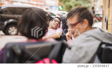 Friends with disability smiling enjoying conversation outdoors Friends with disability smiling enjoying conversation outdoors 135839817