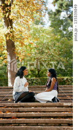 Indian women friends having conversation on park stairs Indian women friends having conversation on park stairs 135839849