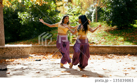Two indian women performing traditional dance in park Two indian women performing traditional dance in park 135839863