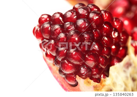 A close up of a red pomegranate fruit with a lot of seeds A close up of a red pomegranate fruit with a lot of seeds 135840263
