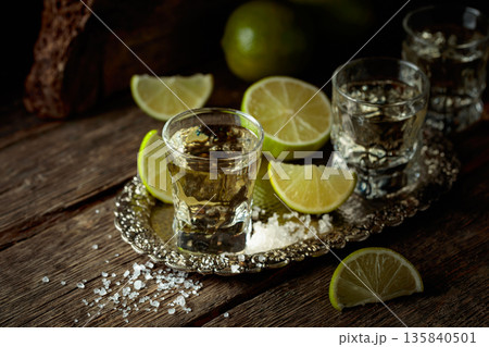 Tequila with salt and lime slices on a silver tray. Tequila with salt and lime slices on a silver tray. 135840501