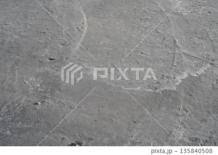 The gray surface of drying hand-mixed concrete. Waves of lime from river sand and the silhouettes of crushed stone edges appearing on the surface as the cement mortar dries. Backdrop with a beach vibe 135840508