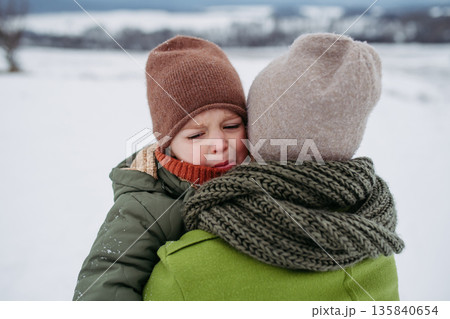 Mother comforting crying child after winter accident. Mother comforting crying child after winter accident. 135840654