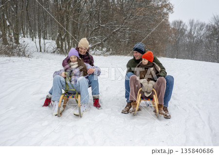 Family enjoying winter sledding together on snowy hill. Family enjoying winter sledding together on snowy hill. 135840686