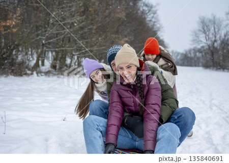 Family enjoying winter sledding together on snowy hill. 135840691