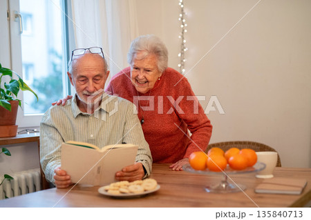 Older couple bonding and talking about book. 135840713