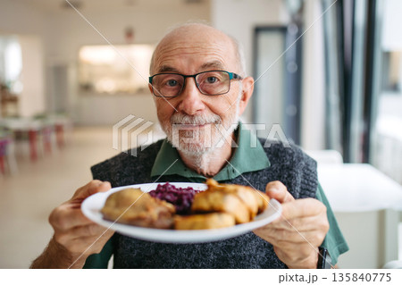 Senior man enjoying lunch at community dining hall. Senior man enjoying lunch at community dining hall. 135840775
