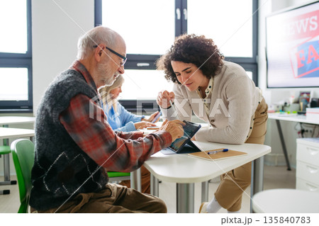 Senior man learning digital skills in community center. 135840783