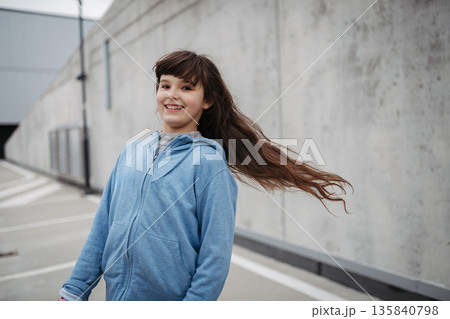 Outdoor portrait of young girl with long hair standing on playground in the city. Outdoor portrait of young girl with long hair standing on playground in the city. 135840798