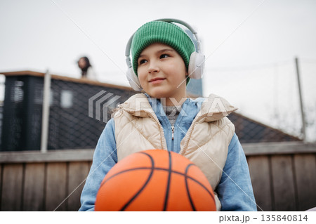 Young girl spending free time playing basketball in the city. Young girl spending free time playing basketball in the city. 135840814
