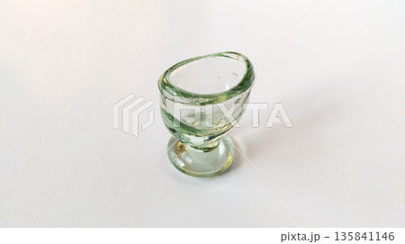 Antique retro glass eye wash cup isolated on white background. Retro eye wash cup made of transparent glass Antique retro glass eye wash cup isolated on white background. Retro eye wash cup made of transparent glass 135841146
