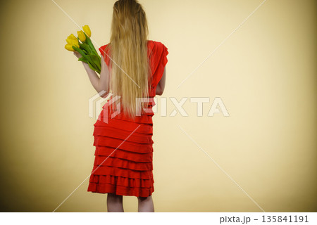 woman with yellow tulips bunch, back view 135841191