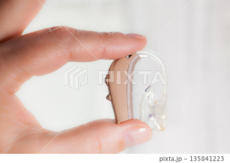 senior person holding hearing aid closeup senior person holding hearing aid closeup 135841223