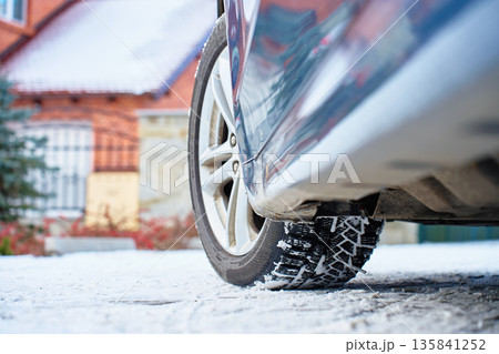 Car with winter tires parked on snowy road near house Car with winter tires parked on snowy road near house 135841252