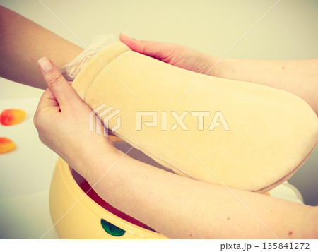 Woman getting paraffin hand treatment at beautician 135841272