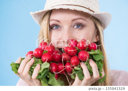 woman holding radish close to face 135841329