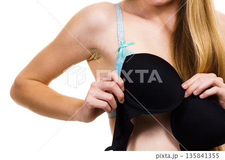 Woman trying on black bra Woman trying on black bra 135841355