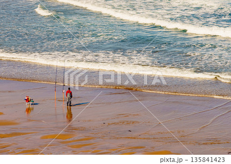 Angler with fishing rod on sea shore 135841423