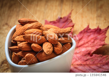 Almonds in bowl on autumnal background 135841546