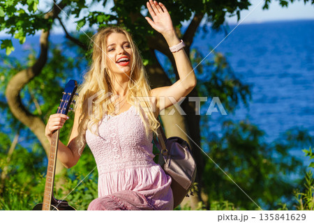 Girl with guitar outdoor on nature 135841629