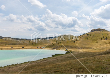 A tranquil countryside scene showing rolling golden hills and turquoise lake A tranquil countryside scene showing rolling golden hills and turquoise lake 135841797