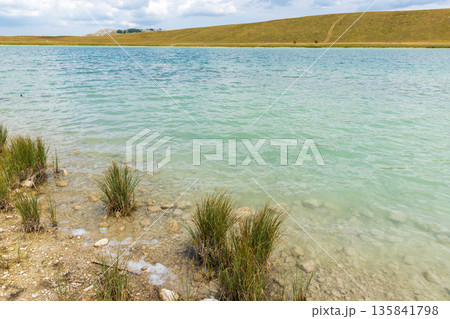A tranquil turquoise lake lapping a rocky, pebbled shore A tranquil turquoise lake lapping a rocky, pebbled shore 135841798