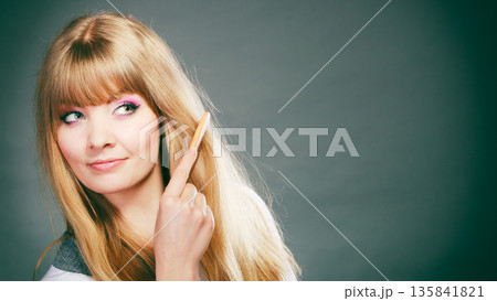 Woman combing her hair with comb Woman combing her hair with comb 135841821