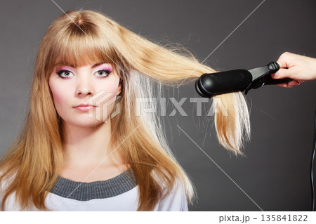 woman making hairstyle with hair iron woman making hairstyle with hair iron 135841822