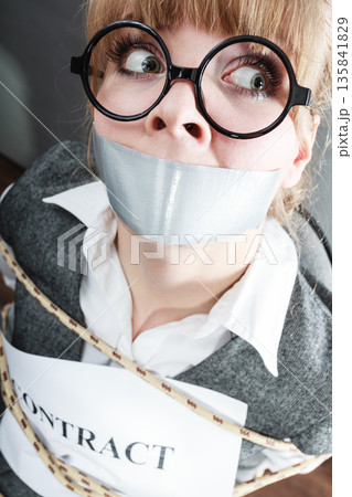 Businesswoman bound by contract with taped mouth. Businesswoman bound by contract with taped mouth. 135841829