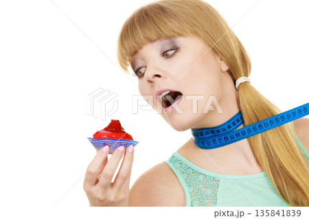 Woman holds cupcake trying to resist temptation 135841839