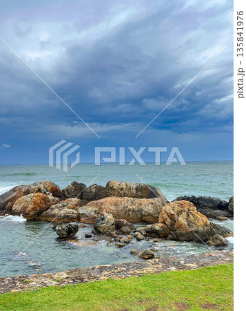 A rocky shoreline with a body of water in the background. 135841976