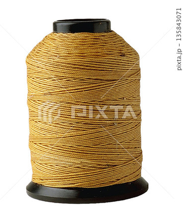 a Large Spool of Golden Yellow Thread on Black Bobbin 135843071
