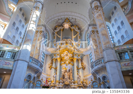 Visitors explore the interior of Frauenkirche in Dresden, Germany. The dome and ornate details showcase the church's architecture. Light filters through the windows, illuminating the space. Visitors explore the interior of Frauenkirche in Dresden, Germany. The dome and ornate details showcase the church's architecture. Light filters through the windows, illuminating the space. 135843336