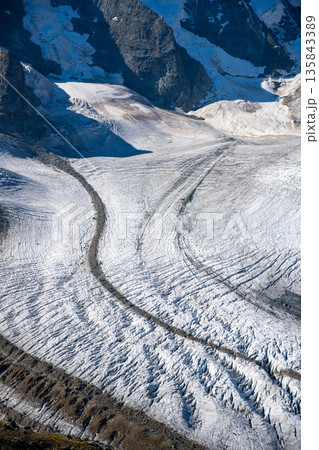 The dramatic Pers Glacier stretches across the Bernina Range, showcasing its vast icy surface and rugged alpine surroundings under clear skies in Switzerland. The dramatic Pers Glacier stretches across the Bernina Range, showcasing its vast icy surface and rugged alpine surroundings under clear skies in Switzerland. 135843389