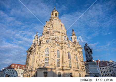 Frauenkirche stands tall in Dresden, Germany. Visitors admire the church structure and dome under a clear sky. The atmosphere is festive with decorations for Christmas. Frauenkirche stands tall in Dresden, Germany. Visitors admire the church structure and dome under a clear sky. The atmosphere is festive with decorations for Christmas. 135843630