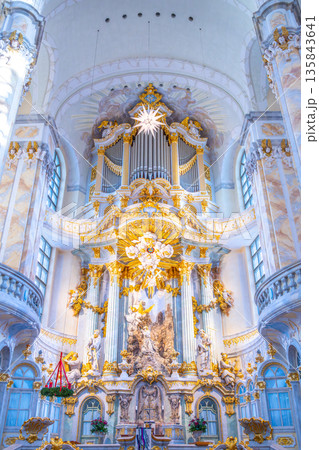 The interior of Frauenkirche in Dresden features a large dome, detailed decorations, and a grand altar. Visitors admire the artwork and architecture in this historic church. The interior of Frauenkirche in Dresden features a large dome, detailed decorations, and a grand altar. Visitors admire the artwork and architecture in this historic church. 135843641