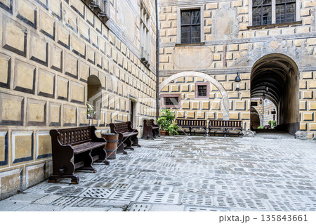 Tourists explore the courtyard of Cesky Krumlov Castle in Czechia during summer. Benches line the walls, and plants add greenery to this historic site recognized by UNESCO. Tourists explore the courtyard of Cesky Krumlov Castle in Czechia during summer. Benches line the walls, and plants add greenery to this historic site recognized by UNESCO. 135843661
