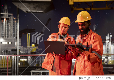 Offshore diverse workers monitoring drilling rig systems and activity with devices, managing natural gas and petroleum extraction from industrial platform. Oil and gas production for industry. Offshore diverse workers monitoring drilling rig systems and activity with devices, managing natural gas and petroleum extraction from industrial platform. Oil and gas production for industry. 135844460