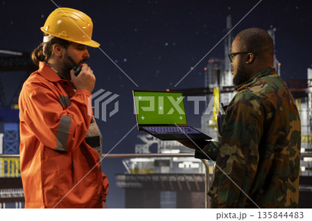 Green screen laptop used by soldier protecting strategic national energy assets on sea drilling rig. Military unit on offshore platform deck perimeter to deter hostile actions using mockup notebook Green screen laptop used by soldier protecting strategic national energy assets on sea drilling rig. Military unit on offshore platform deck perimeter to deter hostile actions using mockup notebook 135844483