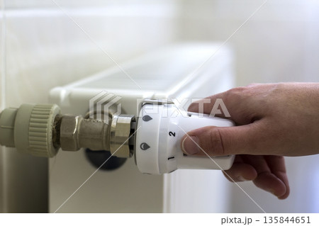 Hand adjusting the valve knob thermostat of heating radiator Hand adjusting the valve knob thermostat of heating radiator 135844651