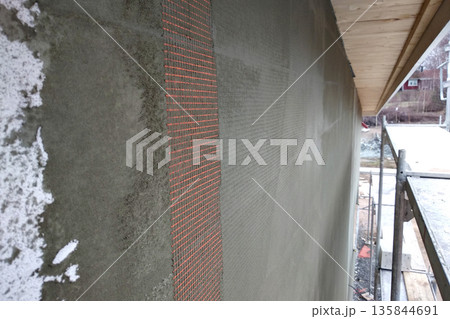 Closeup of layers over styrofoam insulation, mesh, plaster, cement, mortar, solution of glue. 135844691