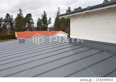 Close-up detail of house roof made from gray metal sheets. Close-up detail of house roof made from gray metal sheets. 135844693
