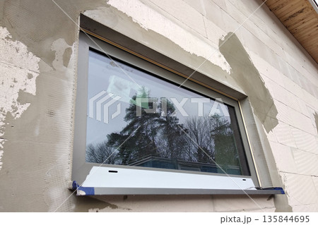 Facade of building made from white blocks with big windows under construction works. Facade of building made from white blocks with big windows under construction works. 135844695