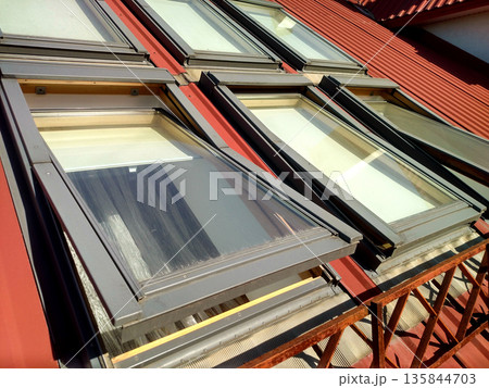 Red tiled house roof with attic windows. Roofing construction, window installation, modern architecture concept. Red tiled house roof with attic windows. Roofing construction, window installation, modern architecture concept. 135844703